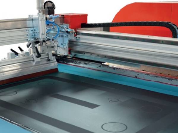 A machine is screen printing home appliance glass.