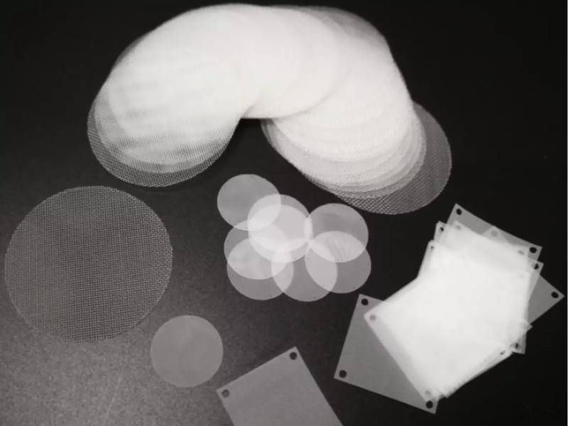 Several pieces of nylon mesh filter discs on black background.