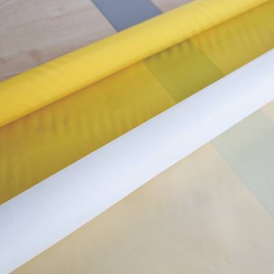 A roll yellow and a roll white polyester mesh on the ground.