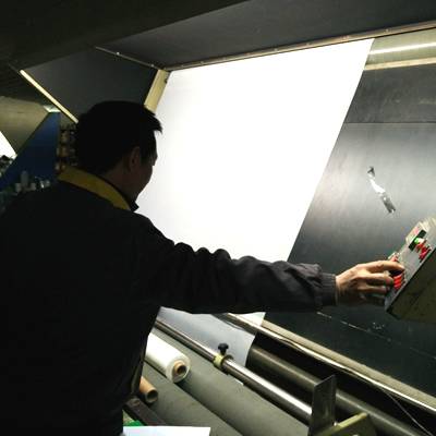 Two workers are inspecting and cutting polyester mesh.