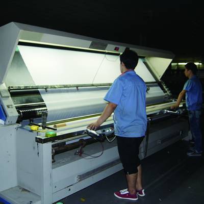 Two workers are inspecting the polyester mesh.