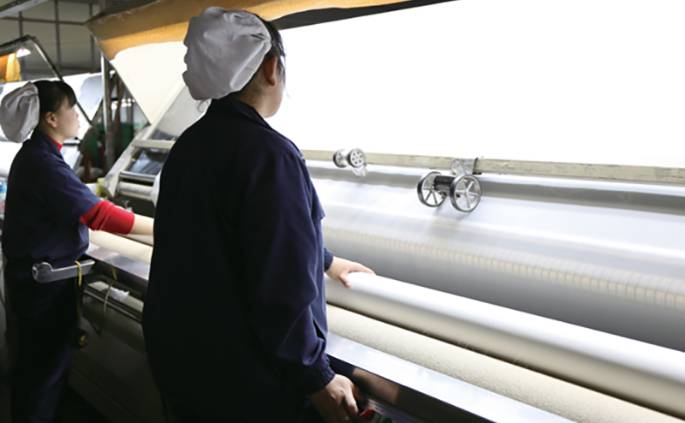 Two workers are testing the polyester screen mesh.