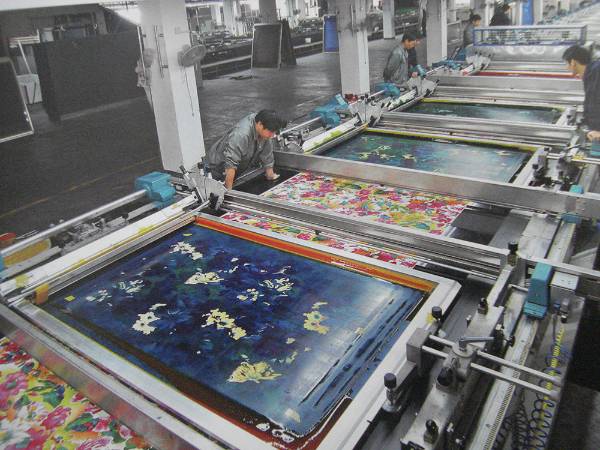 A rotary screen printing machine is printing silk fabrics.