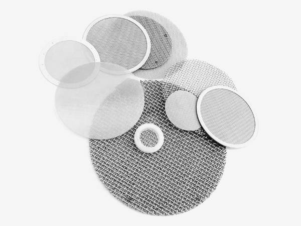 Several pieces of stainless steel mesh filter discs on gray background.
