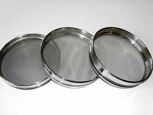 Three pieces of stainless steel test sieves on gray background.